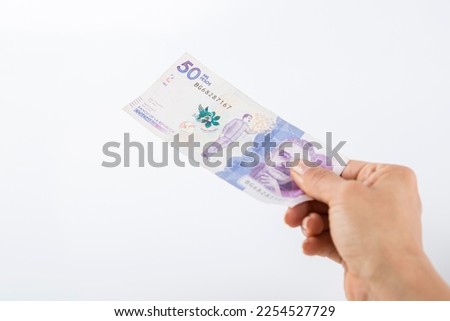 a person hands over a fifty thousand colombian peso bill