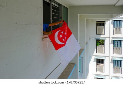 Person Hanging Singapore Flag Outside HDB Apartment Windows, To Welcome National Day