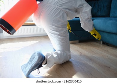 Person In Hazmat Suit Disinfects Living Room With Spray Gun