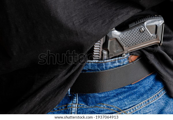 A person is hiding a handgun under\
the denim belt. Hided handgun under the denim\
belt.