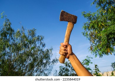 Person holding axe in hand with the sky in the background