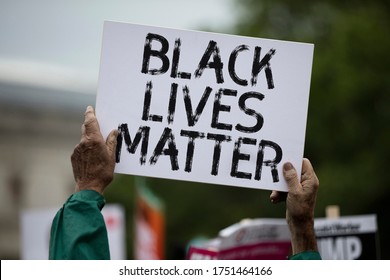 A Person Holding A Black Lives Matter Banner At A Protest