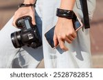 A person is holding a camera and a cell phone in their hands. The camera is a Canon EOS 5D Mark IV, and the cell phone is a Samsung Galaxy S5