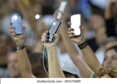 Person Holding A Cellphone With The Flash On And Hands Up