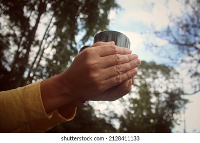 Person Holding Cup Of Tea Or Coffee In Hands. Woman With Glass Of Water In Hand. On Green Nature Park Background. Relax And Breaking Time Concept.