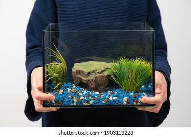 Person holding fish tank aquarium with no water and fish on white background. Fist pet.
