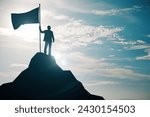 Person holding a flag on top of a mountain peak silhouetted against the sky, symbolizing victory and achievement