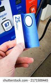 Person Holding A Generic Gas Gift Card In Hand And Paying At The Gasoline Pump Station. Rising Gas Prices And Payment Options