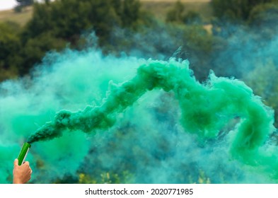 A Person Holding A Green-colored Smoke Bomb In The Air