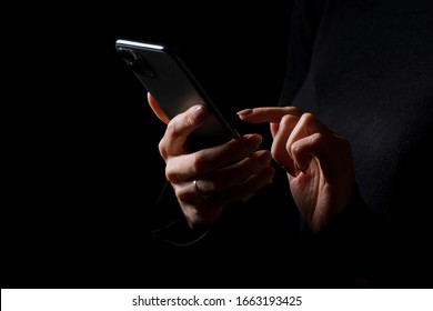 Person holding in hands and typing on mobile phone, photo isolated on black background