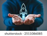 Person holding a holographic rocket launching above their hands, symbolizing innovation and startup success.