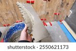 A person holding a notched trowel applies adhesive for tiling, symbolizing home renovation and DIY projects