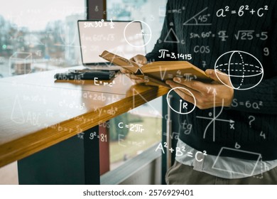 A person holding an open book surrounded by overlaid mathematical formulas, with laptop on wooden table in background. Education, science, and technology in modern setting.