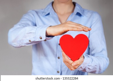 A Person Holding And Protecting A Heart Symbolizing Safety, Love And Health