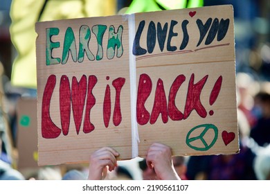 Person Holding Protest Sign Saying Earth Loves You Love It Back. Climate Change Protest. Love The Earth Message.