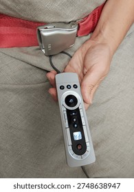 Person is holding a remote control with a timer on it. The remote control is on a grey surface in airplane
