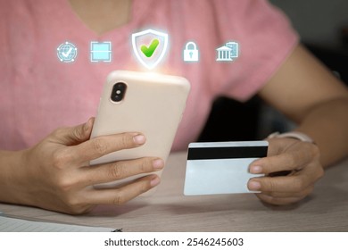 A person holding a smartphone and a credit card, with digital security icons above, representing safe online payment. - Powered by Shutterstock