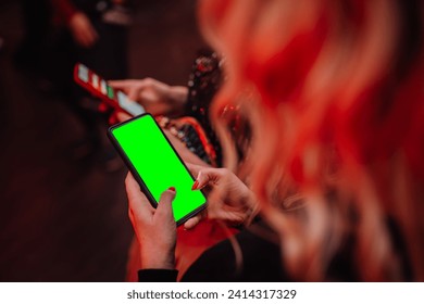 person holding a smartphone with a green screen, likely for chroma key compositing, with a blurred background. - Powered by Shutterstock