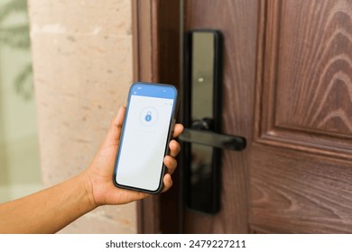 Person is holding a smartphone unlocking a smart lock system of an apartment door with a digital key - Powered by Shutterstock