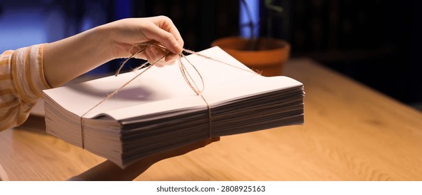 Person holding stack of blank papers tied with string
