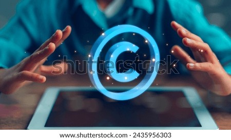 A person is holding their hands up to a tablet with a copyright symbol on it. Concept of protecting intellectual property and the importance of copyright laws