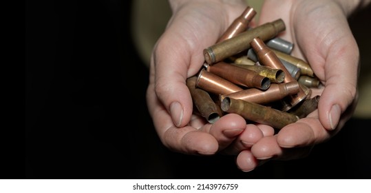 Person Holds Bullet Casings From Different Types Of Firearms On Black Backdrop. War In Ukraine Against Russia. Used Cartridges In Human Hands. Pray For Peace On Earth. The Terrible Truth Of Bloody War