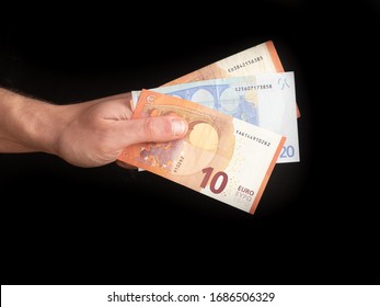 Person holds euro money in hand isolated on black. 