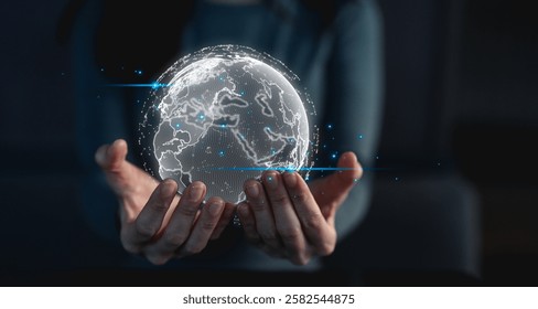 A person holds a glowing, digital globe, symbolizing technology, connectivity, and a global perspective in a dark setting.