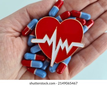 Person Holds Heart Pills And Cardiological Heart In Hand. Cardiovascular Disease Symptoms And Treatment Concept