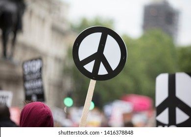 A Person Holds A Peace Sign Banner At A Protest