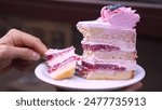 A person holds a piece of cake with a missing slice, tempting and delicious. Perfect for dessert lovers craving a sweet treat. Enjoy the indulgence!