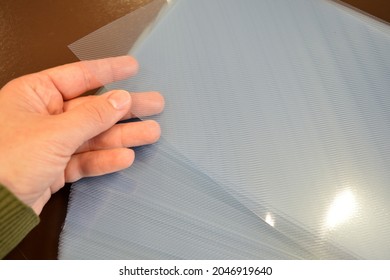 Person Holds A Translucent Rigid PVC Sheet At An Office Table.