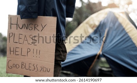 Person, homeless and hungry with cardboard for begging by tent, poverty or ask for food at park. Sign, outdoor and poster for donation, care and need for kindness with hope for charity meal in winter
