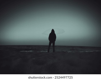 A person in hoodie in silhouette standing by the sea watching it. - Powered by Shutterstock