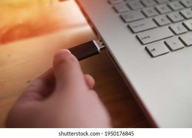 Person inserting plug in flashdisk into usb port in laptop personal computer, data transfer device concept, close up