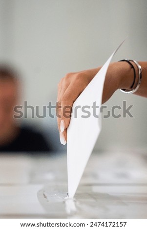 A person inserts a ballot in a box while voting at a polling station during elections.