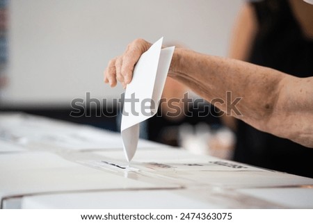 A person inserts a ballot in a box while voting at a polling station during elections.
