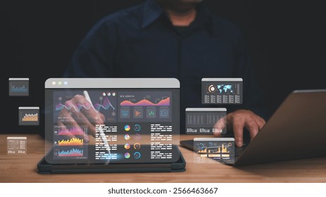 Person interacts with digital interface showing various analytical data visuals and charts while working on laptop, demonstrating integration of technology and data analysis