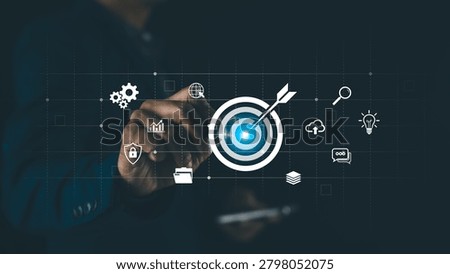 A person interacts with a digital interface showing a target with an arrow, surrounded by icons representing business, security, data, and innovation.