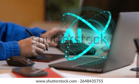 Person interacts with digital pad while AI hologram glows beside laptop, symbolizing artificial intelligence and human-computer interaction in creative tech work. Concept of future of work