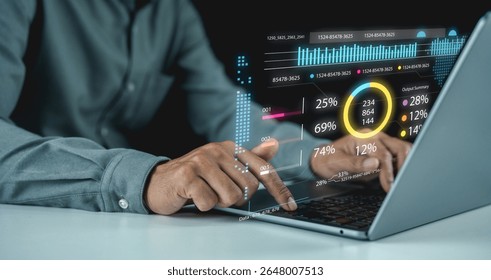 A person interacts with a laptop displaying futuristic data charts and analytics in a digital holographic interface.