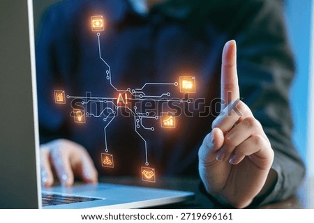 A person interacts with a laptop, using a finger to point at floating graphics representing various aspects of artificial intelligence.