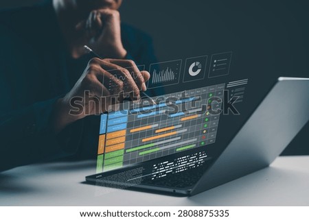 A person interacts with a virtual data interface displaying charts and graphs above a laptop in a dark, focused setting.