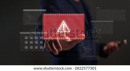 A person interacts with a virtual interface displaying a digital warning symbol and code, highlighting cybersecurity and data protection concerns.