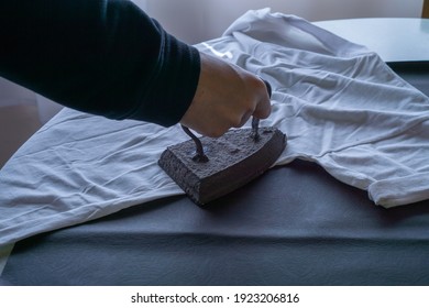 Person Ironing With Old Iron On Wrinkled Clothes