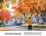 A person jogging in a suburban neighborhood with vibrant autumn foliage on a sunny morning