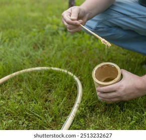 A person is kneeling on the grass and holding a paintbrush. They are painting a garden hose - Powered by Shutterstock