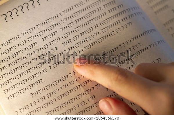 A person leads a finger on the lines in the\
book, but instead of letters only question marks on the page in the\
textbook.