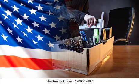 A Person Leaves The Workplace Against The Background Of The US Flag. Unemployment In America. Economic Collapse. Lack Of Jobs. Bankruptcy Of Firms In The United States. Ruin Of Entrepreneurs. 