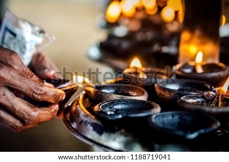 A person lights a candle in a Buddhist temple. Kalutara. Sri Lanka.
